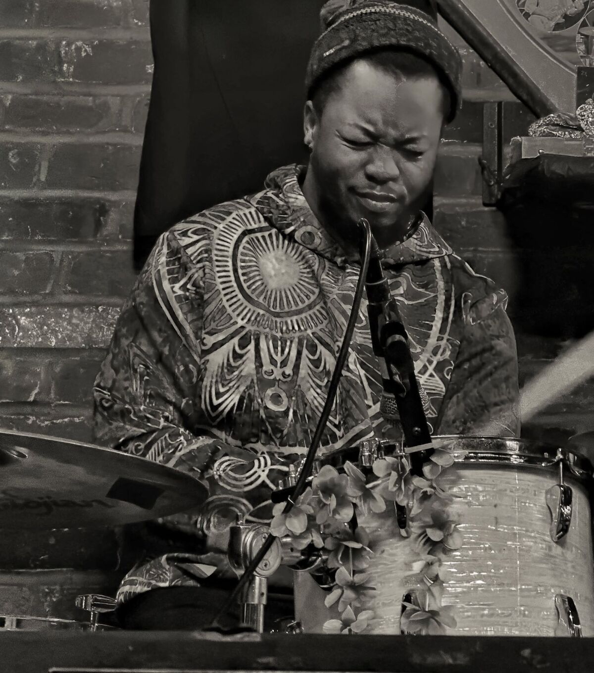 Reggie Taber playing drumset on stage, eyes closed, in a patterned shirt